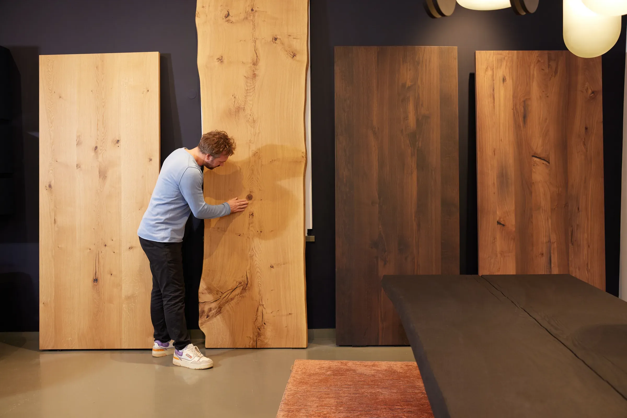Niels Klün begutachtet eine Tischplatte mit Naturkante im Showroom