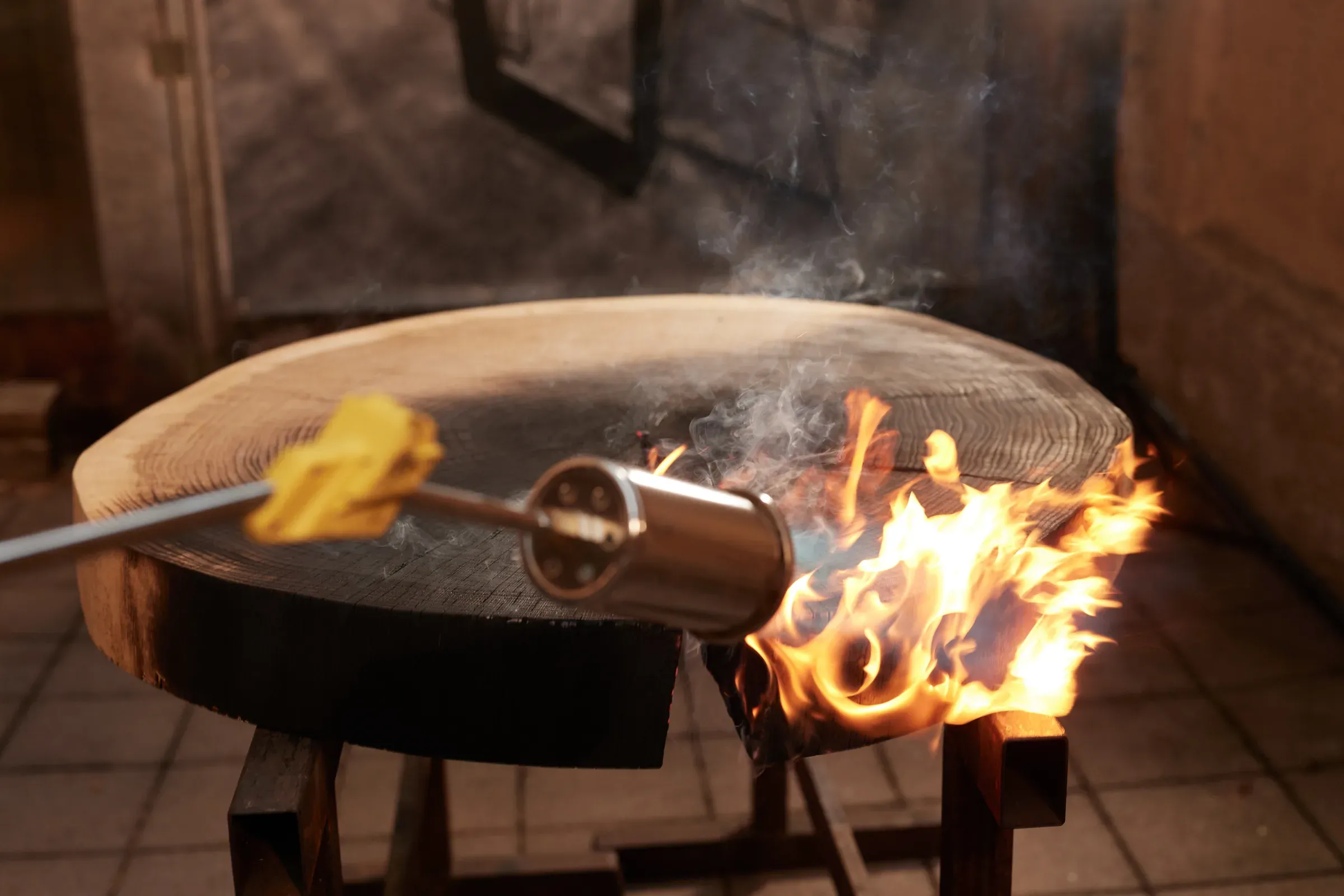 Eine Baumscheibe wird mit dem Gasbrenner beflammt