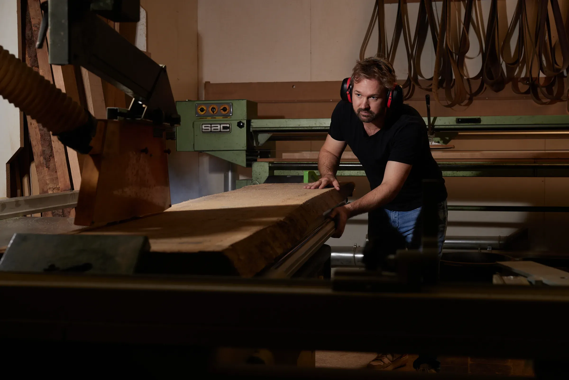 Eine Holzbohle wird an der Säge zugeschnitten